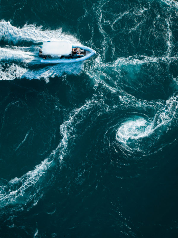 A group of tourists on a boat travel through the whirlpools of water on a Sea Safari.