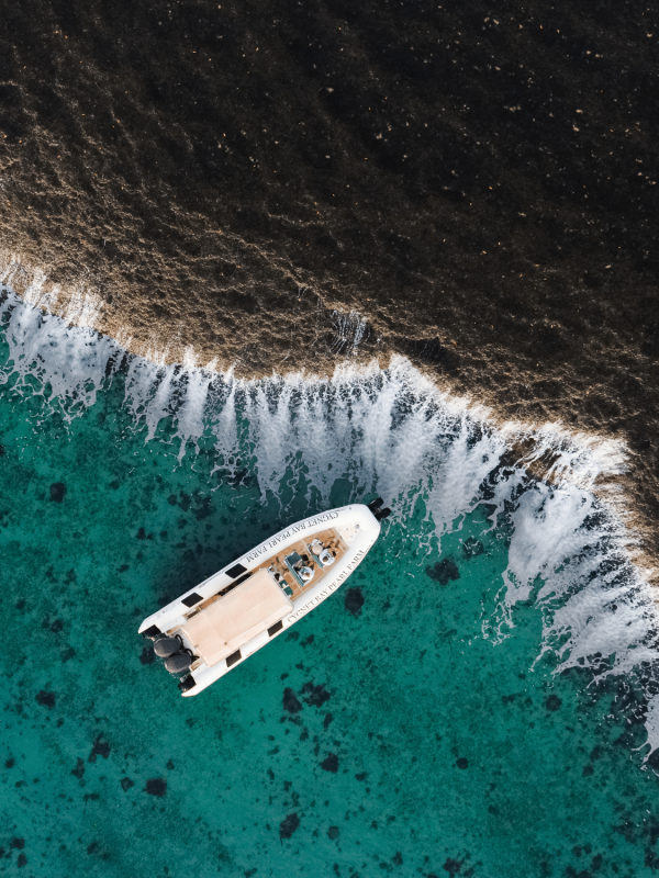 Waterfall Reef Sea Safari A Cygnet Bay boat sits idly next to the iconic Waterfall Reef, spilling water during the low tide of the ocean. The guests on the boat bare witness to this unique natural phenomenon and are in awe of it's cascading waterfall effect.