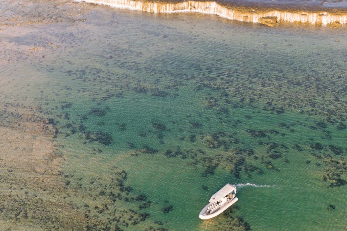 A Cygnet Bay boat sits idly next to the iconic Waterfall Reef, spilling water during the low tide of the ocean. The guests on the boat bare witness to this unique natural phenomenon and are in awe of it's cascading waterfall effect. Our Planet.