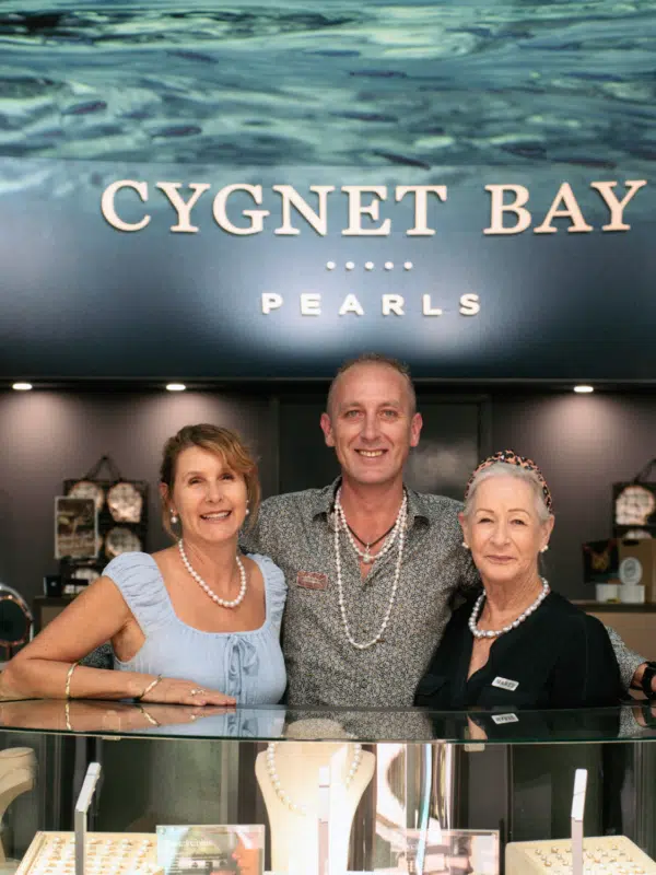 Photo of our Broome Showroom team members smiling at the front of the store, standing behind a cabinet filled with our stunning locally grown Australian South Sea and Australian Akoya pearls set in gorgeous designs.