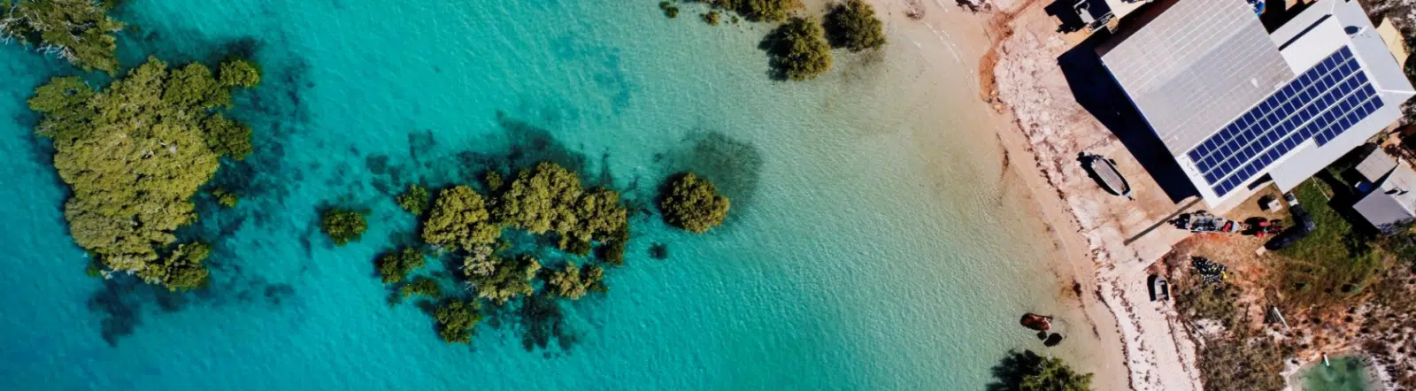 An aerial photo of Cygnet Bay's turquoise waters, the mangroves, and the pearling shed. CBPF Accessibility Guide.