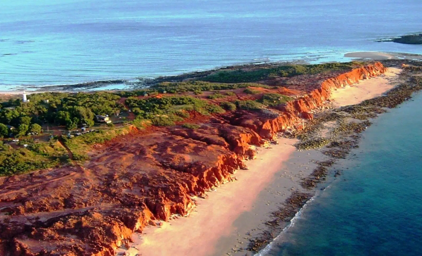 An aerial photo of the Dampier Peninsula's red rock faces, the white sandy beaches and azure blue waters of Cygnet Bay.