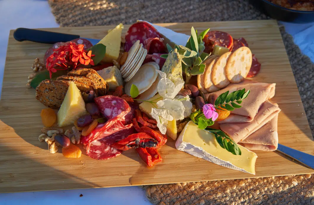 A charcuterie board with cold cut meats, soft cheeses, nuts, and crackers for guests to enjoy. Our Dining.
