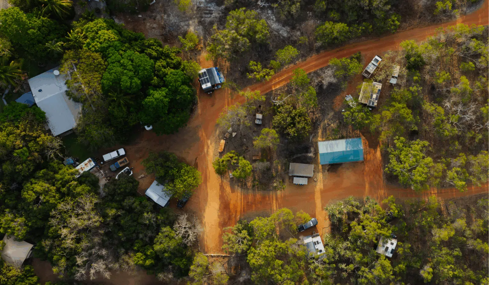 An aerial view of the stunning, rugged landscape of the Dampier Peninsula's terrain and dirt roads to multiple camping and caravan locations for vacationers to pitch a tent up at. Each camp site is surrounded by native, Australian plants that create privacy for the campers - a truly serene experience.