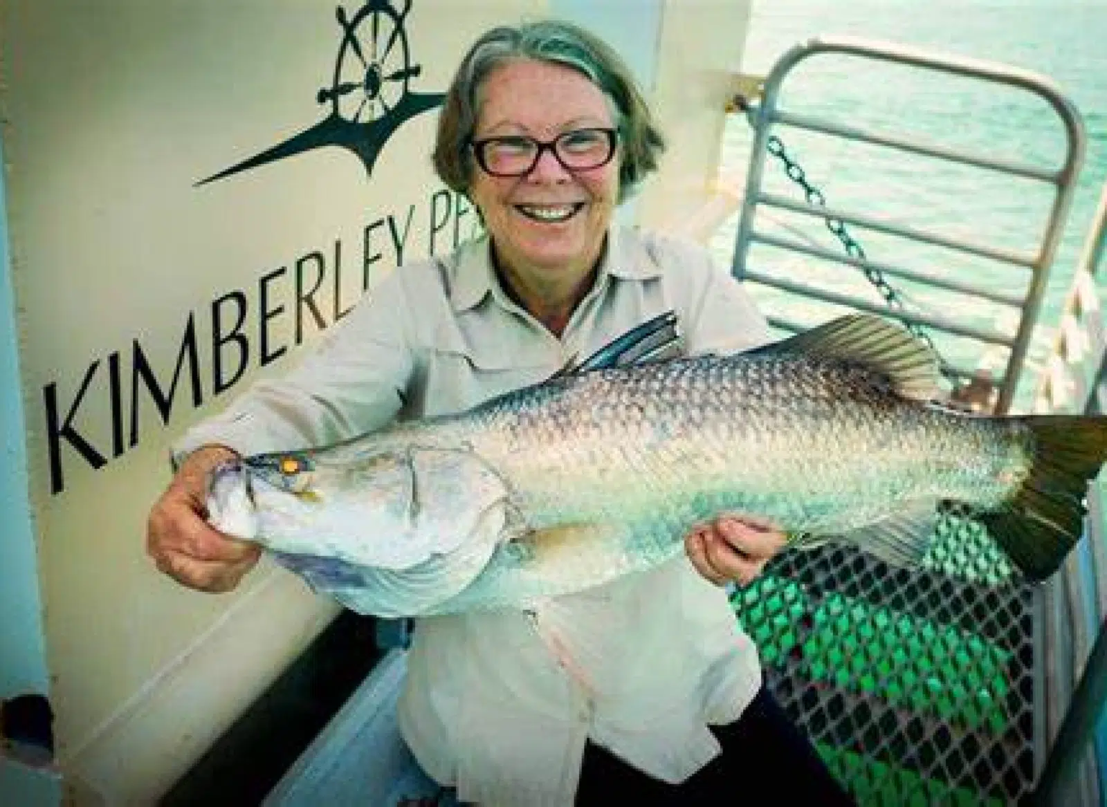 A lady holds a fish she has just caught while on a boat tour in the Kimberley.