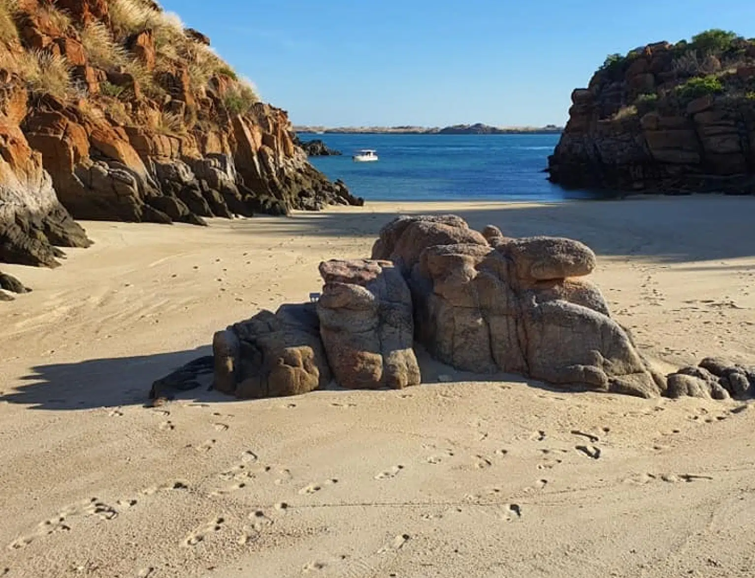 A secluded beach with a boat with excited guests ready to explore.