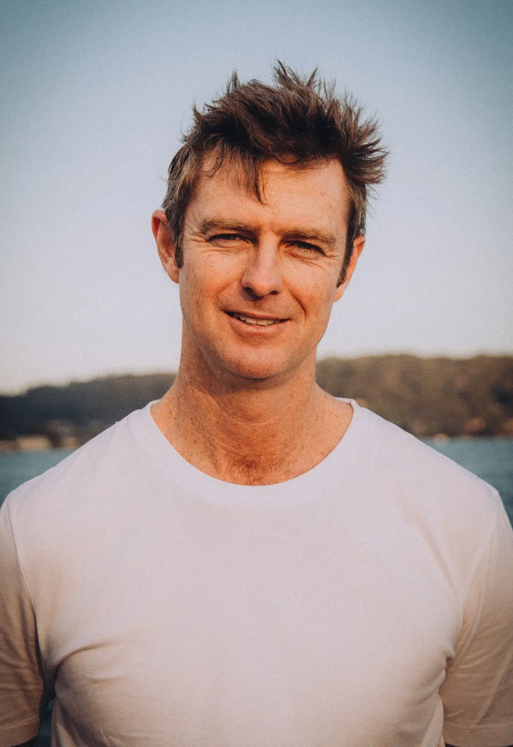 James Brown, the Managing Director of Pearls of Australia, stands on a pier at Broken Bay Pearl Farm with the sunset lighting his face.