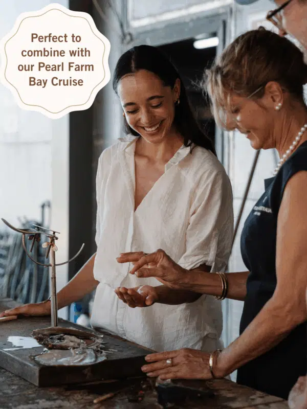 A group of guests enjoy a Pearl Farm Harvest Tour, where a tour guide holds open an Australian South Sea oyster in one hand, and the Australian South Sea pearl in the other - showcasing a Live Pearl Harvest!