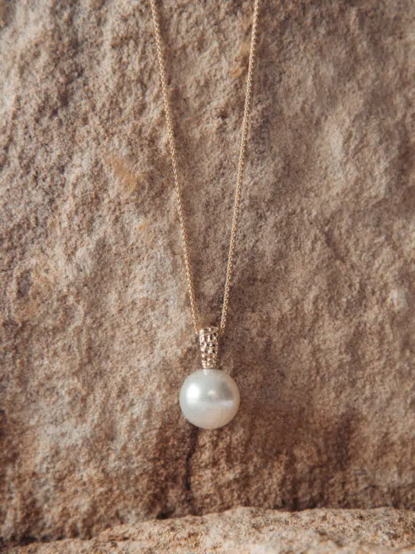 An Impressions Pendant rests against sandstone, and is delicately hung on a yellow gold chain. This pendant features an Australian South Sea pearl, grown at our very own Cygnet Bay Pearl Farm.