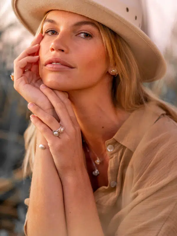 A model wears the Kimberley Lily Keshi Pearl Jewellery Collection while enjoying the beautiful Kimberley sunrise. She wears three rings, all of varying metals, two pendants on matching chains, and a pair of studs. All featured pearls are locally grown at our Cygnet Bay Pearl Farm.