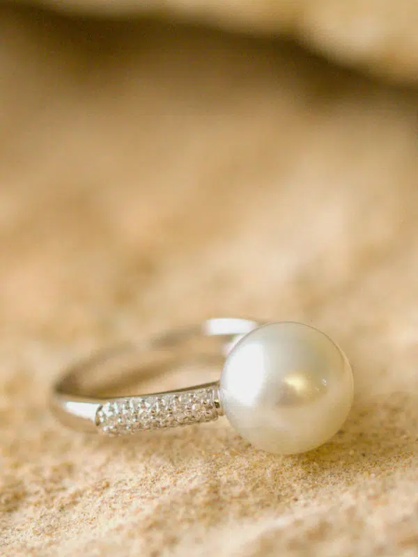 A Dusty Ring sits on sandstone. This ring features our locally grown Australian South Sea pearl set on gold and surrounded by a myriad of white diamonds on either side of the pearl.