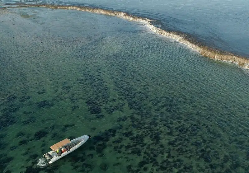 A Cygnet Bay boat travels to the iconic Waterfall Reef, spilling water during the low tide of the ocean. The guests on the boat bare witness to this unique natural phenomenon and are in awe of it's cascading waterfall effect.